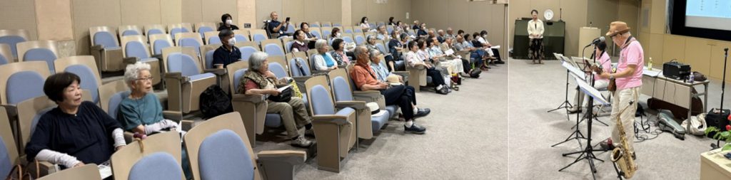 施設のホール内で入居者や家族が集まり、スタッフによる演奏・イベントを鑑賞している様子